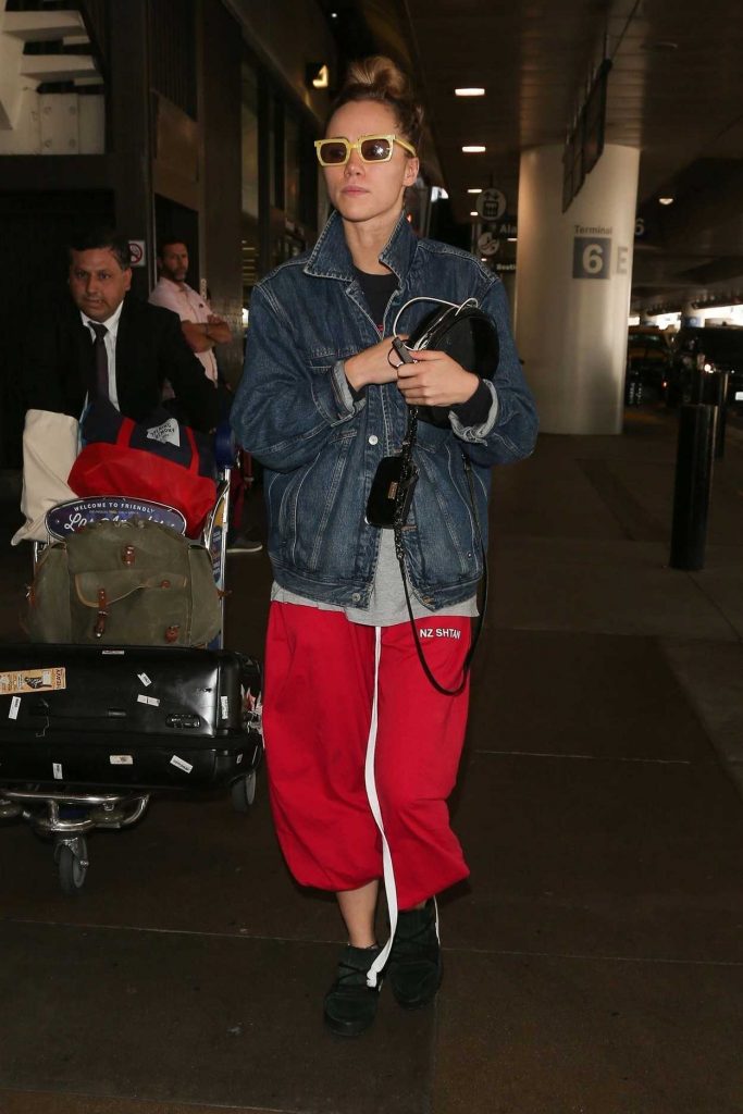 Suki Waterhouse in a Red Natasha Zinko Technical Nylon Joggers Was Seen at LAX Airport in Los Angeles 09/12/2018